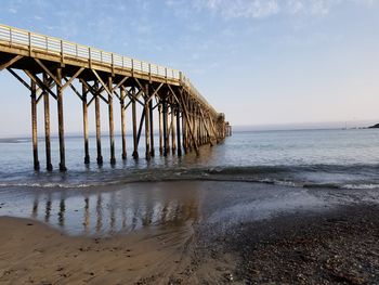 Silhouette of pier on beach against sky