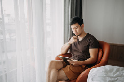 Side view of young woman using laptop at home