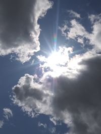 Low angle view of sunlight streaming through clouds