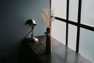 Close-up of vase on table by window at home