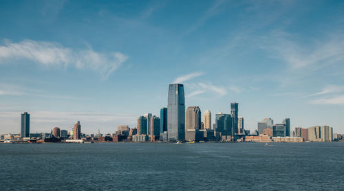 Sea by modern buildings against sky in city