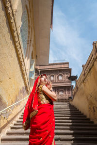 Woman in red sari standing against temple