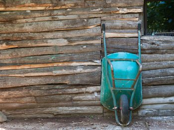 Wheelbarrow leaning on log cabin