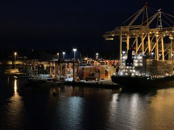 Sailboats moored at harbor against sky at night