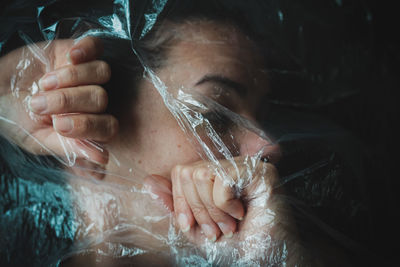 Close-up portrait of young woman holding plastic 