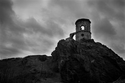 Low angle view of old castle ruin on rock formation against sky