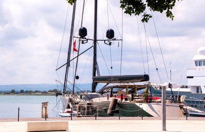 Sailboats moored at harbor against sky