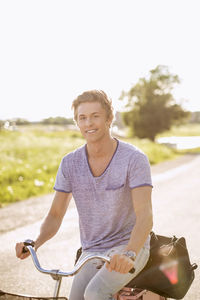 Portrait of happy young man cycling on country road