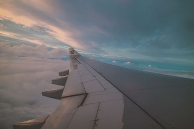 Airplane wing against sky during sunset