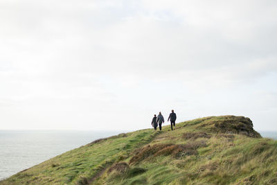 People walking on shore by sea against sky