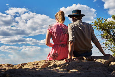 Rear view of people on rock against sky