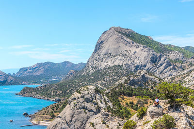 Scenic view of mountain by sea against blue sky