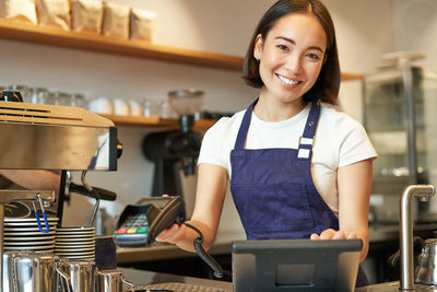 Portrait of young woman standing in cafe