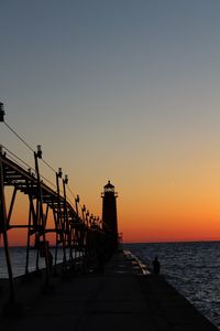 Silhouette pier over sea against sky during sunset