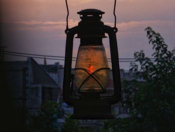 Illuminated electric lamp against sky at sunset
