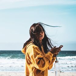 Woman standing at beach against sky