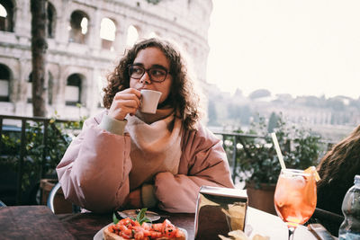 Young woman drinking coffee while sitting on table