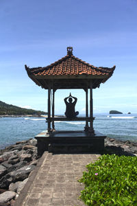 Gazebo in sea against blue sky