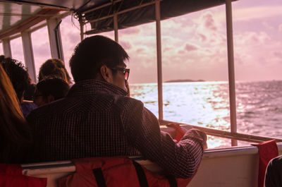 Rear view of man sailing in ferry against sky