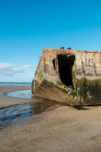 Abandoned built structure on beach against clear blue sky