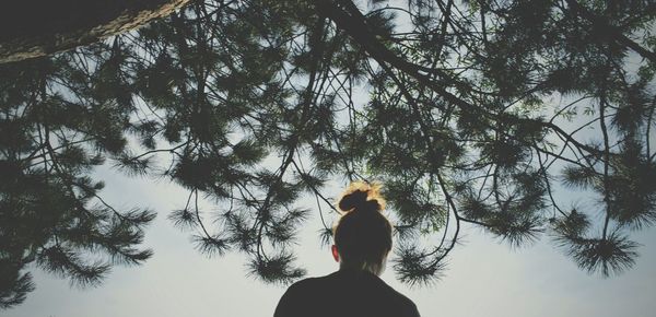 Woman standing by tree trunk