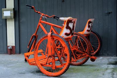 Vintage orange tandem bicycle against wall