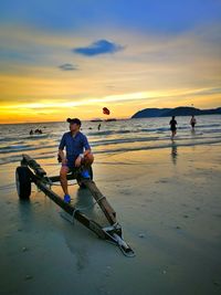 People on beach against sky during sunset