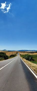 Country road along landscape against blue sky