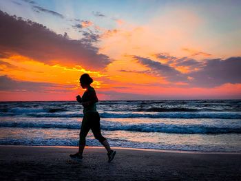 Woman jogging on the beach at sunrise