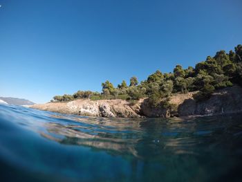 Surface level of sea by rock formation against blue sky