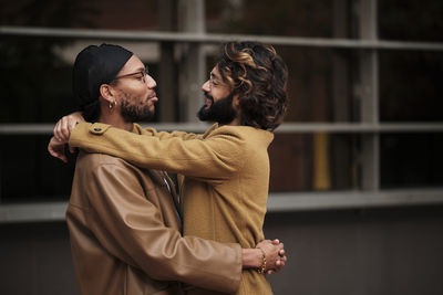 Smiling multiracial gay couple hugging each other