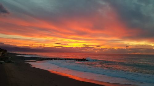 Scenic view of sea against dramatic sky during sunset