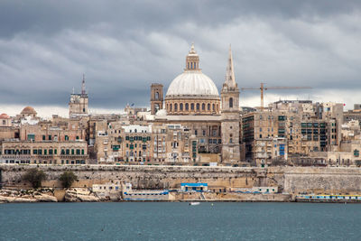 View of buildings in city against cloudy sky