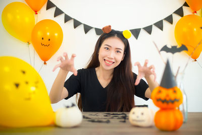 Portrait of cheerful young woman with jack o lanterns at table