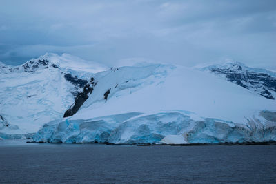 Scenic view of sea and snowcapped mountains against sky