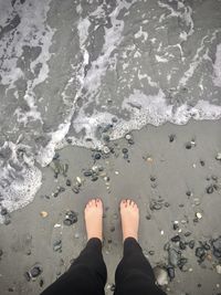 Low section of man standing on beach