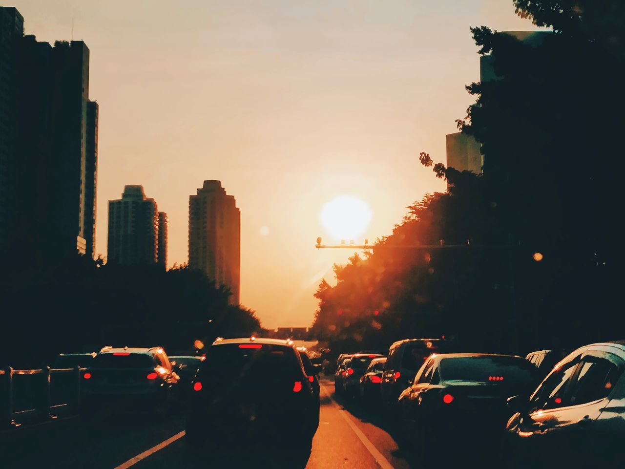 TRAFFIC ON CITY STREET AGAINST SKY DURING SUNSET