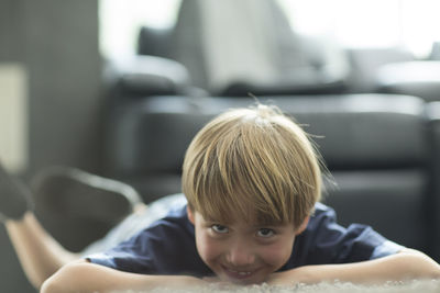 Portrait of smiling boy lying on rug at home