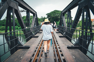 Rear view of woman on footbridge against trees