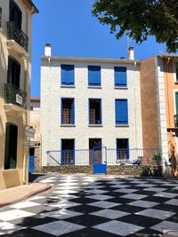 Footpath by building against blue sky