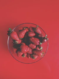 High angle view of strawberries in bowl against red background