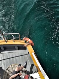 Low section of woman sitting on boat in sea during sunny day