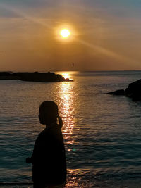 Silhouette man looking at sea against sky during sunset