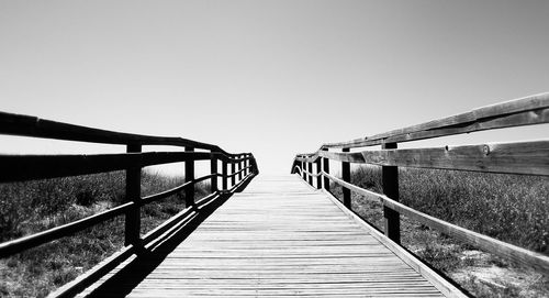 Footbridge over footpath against clear sky