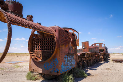 Old rusty ship on beach against blue sky