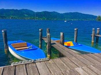 Boats moored in lake against blue sky