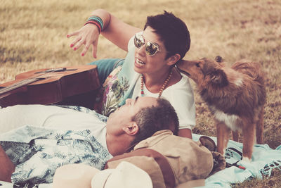 Man and woman with guitar relaxing on grassy field