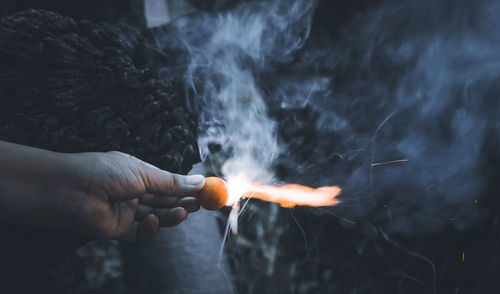 Midsection of person holding burning against fire