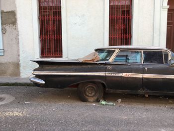 Abandoned car on street against building