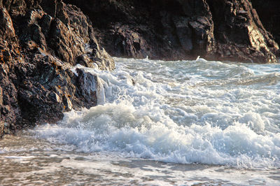 Scenic view of waves breaking on rocks at sea shore
